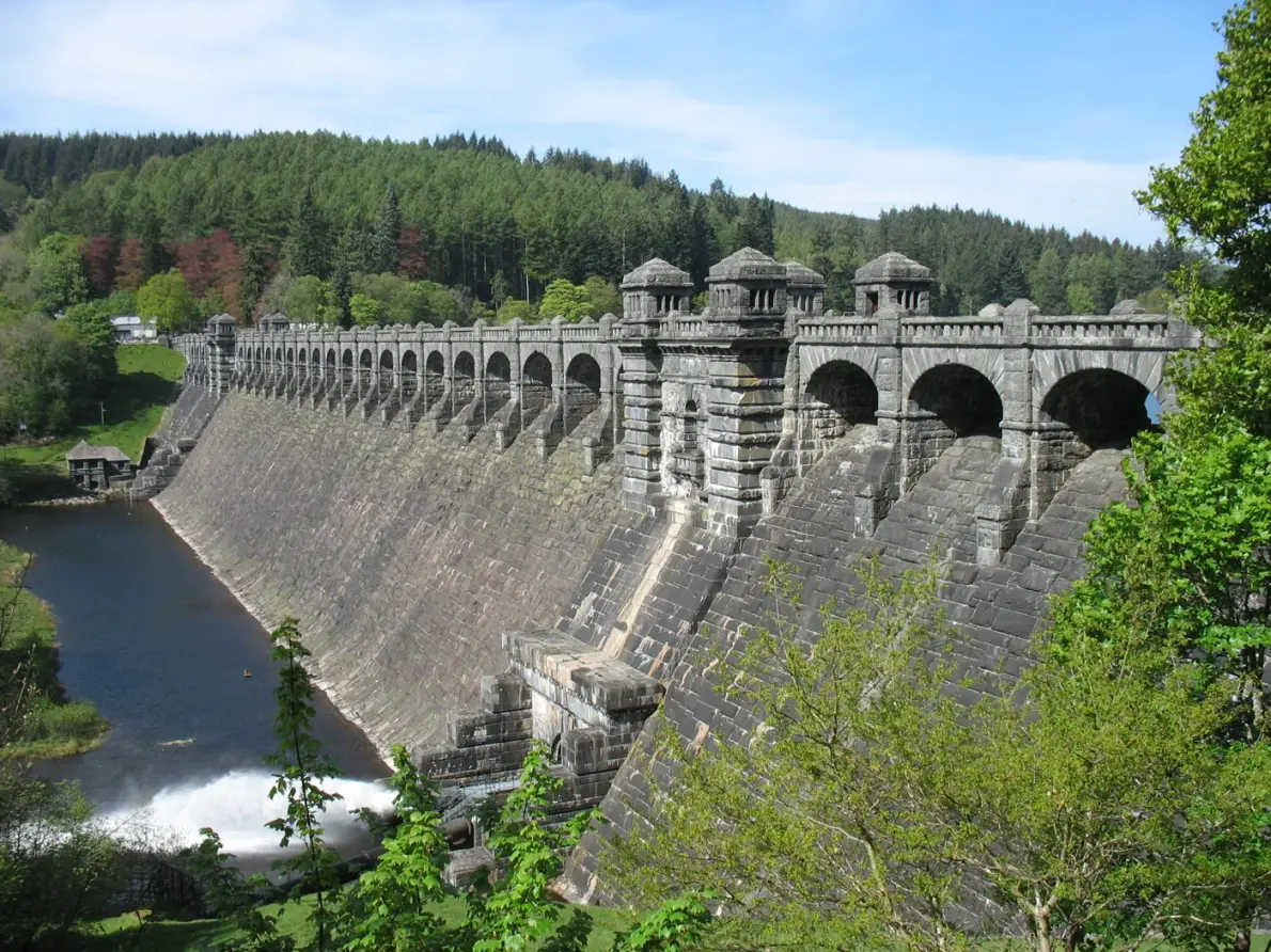 Stone dam across Lake Vyrnwy with wooded hills behind