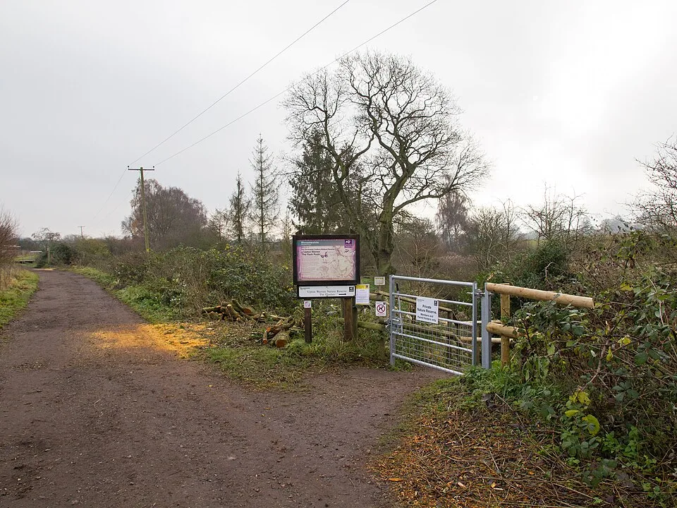Entrance gate and surfaced path at Upton Warren nature reserve, with winter trees and a visitor sign
